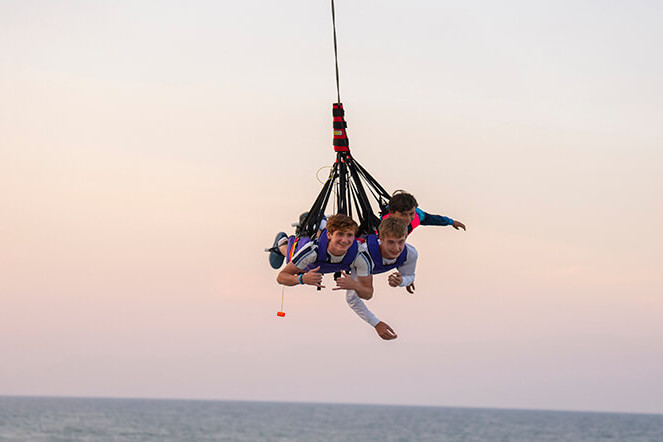 Riders swinging on the SkyCoaster over the ocean