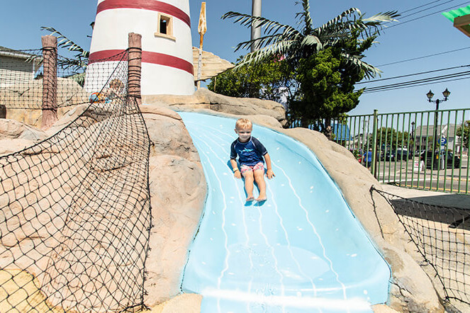 Child sliding down a slide at Lighthouse Cove kids area